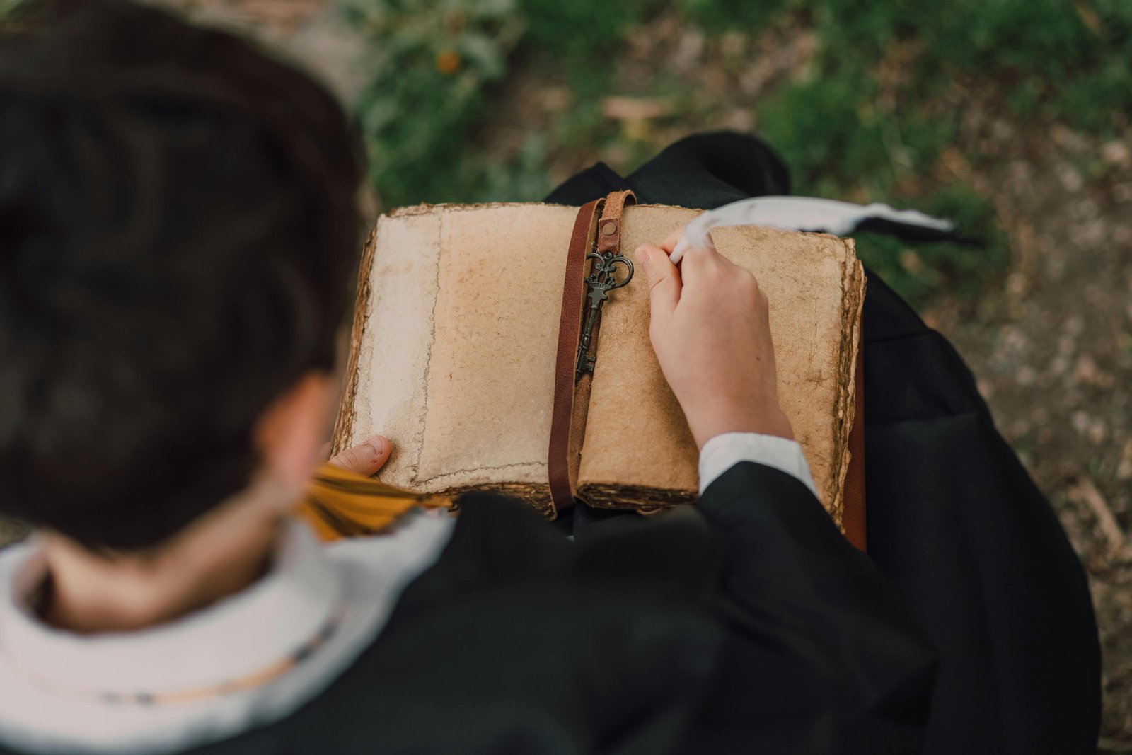 Someone writing in a vintage leather journal with a quill pen
